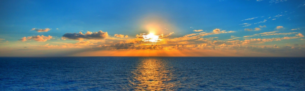sun setting through the clouds over the sea